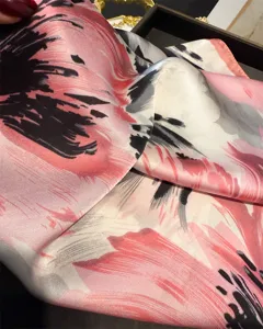 Close-up detail of the pink and black floral printed silk scarf, showing smooth texture.