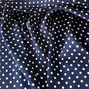 Dettaglio del tessuto in seta a pois blu navy classico, accessorio moda elegante.