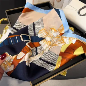 Close-up detail of luxury silk square scarf with elegant harness and floral print design.