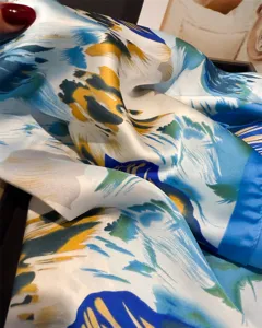 Exquisite silk scarf texture detail closeup featuring an abstract floral print in vibrant blue.