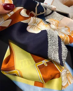 Close-up detail of luxury harness printed silk scarf showing refined smooth fabric texture.