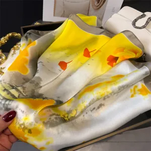 Detailed close-up view of a luxurious yellow and white gradient printed faux silk square scarf.