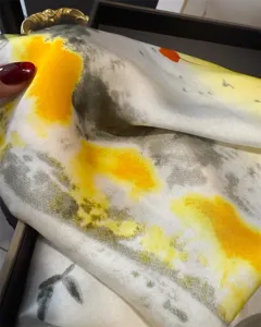 Detailed close-up shot showing abstract yellow and grey printed imitation silk scarf fabric texture.