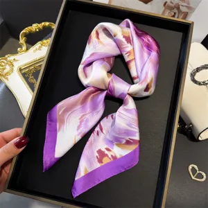 Detailed view of a luxurious purple floral silk square scarf, elegant neck wrap or head accessory.