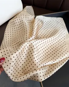 Vista dettagliata di un foulard in seta beige con pois marroni classici ed eleganti.