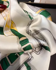 Close-up detail of luxury silk scarf featuring elegant equestrian harness print design.