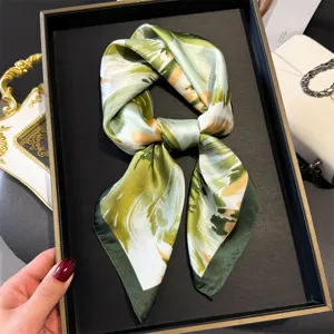 Green abstract printed silk scarf detail close up shot showing smooth fabric texture and tied design.