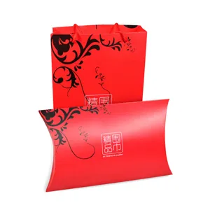 Nahaufnahme von roter Geschenktüte und Kissenbox für Schals mit schwarzem Blumenmuster.