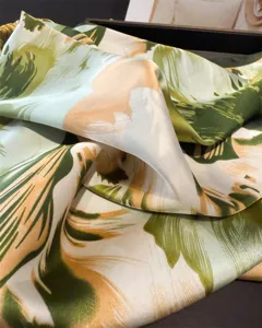 Green and beige abstract floral print silk scarf detail, soft texture and elegant sheen.