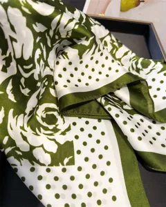 Close-up of green and white floral polka dot silk scarf, elegant rose print accessory for women.