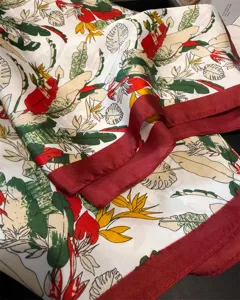 Silk square scarf detail featuring vibrant tropical plant prints and elegant red border.