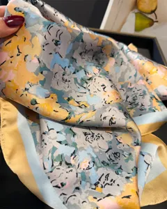 Vue détaillée d'un foulard en soie imprimé élégant avec motif floral coloré et bordure contrastée.