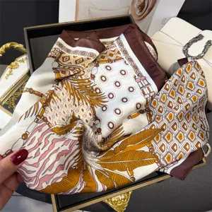 Close-up detail of luxury style printed silk square scarf with elegant feather and chain motifs.