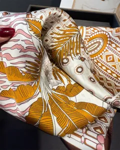 Close-up detail of luxurious silk scarf featuring elegant tropical leaf and geometric print.