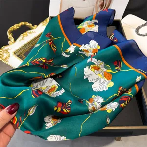 Close-up detail of a luxurious green printed silk square scarf featuring vibrant floral patterns.