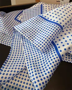 Detaillierter blauer Seidenschal mit klassischem Pünktchenmuster und feiner Kante.