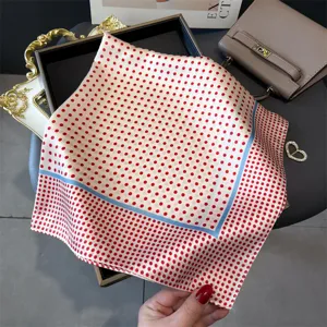 Detailansicht eines eleganten weißen Seidentuchs mit roten Punkten und blauem Rand.