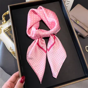 Detailansicht eines rosa Pünktchen-Seidentuchs, elegant geknotet in schwarzer Schachtel.