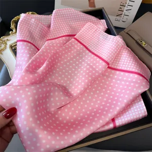 Detailansicht eines rosa Seidenschals mit weißen Punkten und eleganten dunklen Rändern.