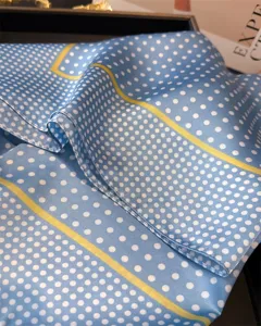 Blaues Seidentuch mit klassischen weißen Punkten und eleganten gelben Randstreifen.