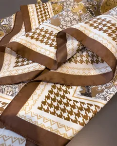 Gros plan détaillé d'un carré de soie de 70cm avec imprimé pied-de-poule et motif floral marron.