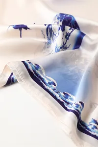 Close-up detail of smooth silky printed scarf featuring elegant blue wave pattern design.