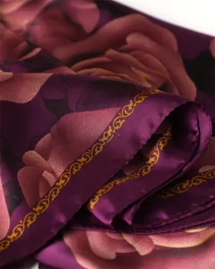 Detailed view of purple silk scarf with elegant floral print and golden baroque style border.