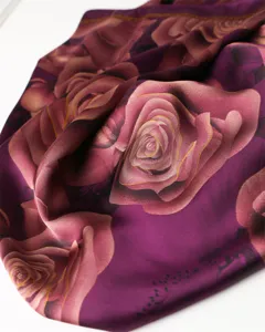 Close-up detail of luxurious purple silk scarf featuring elegant rose floral print texture.