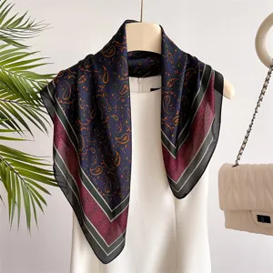 Detailed view of the dark blue paisley printed silk-feel square scarf with elegant borders.