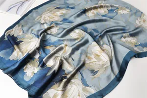 Close-up detail of the elegant blue floral print silk scarf, featuring soft draped satin texture.