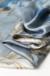 Elegant blue silk scarf fabric detail, showing smooth texture and golden abstract pattern.