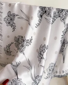 Close-up detail of satin square scarf featuring elegant black floral and celestial print.