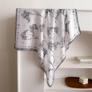 Detailed shot of a black and white floral print imitation silk square scarf draped gracefully.