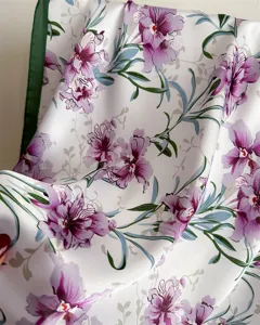 Detail view of 70cm imitation silk square scarf with purple floral print and green edge.