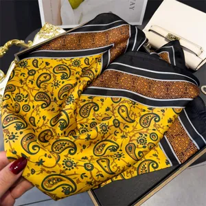 Detailed view of luxury paisley silk square scarf with elegant black and yellow print pattern.