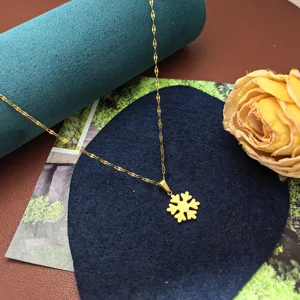 Close-up detail shot of the elegant gold snowflake pendant necklace on a decorative display pad.