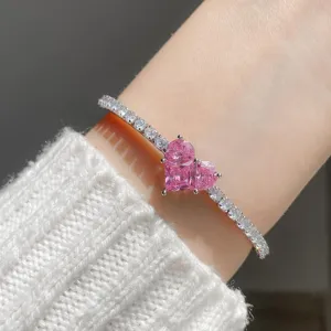 Close-up detail of a stunning pink heart cubic zirconia tennis bracelet on wrist, elegant design.