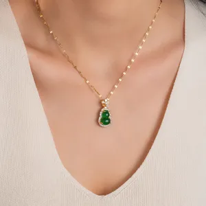 Close-up detail of green gourd pendant necklace with shiny gold chain and sparkling stones.