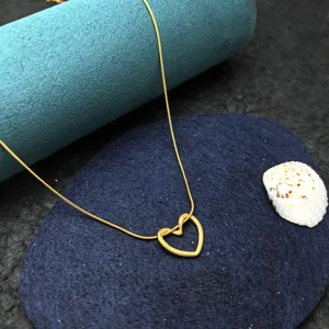 Detailed close-up of the delicate gold-tone open heart pendant necklace on dark display.