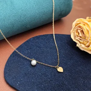 Collana dettaglio in acciaio titanio dorato con perla e ciondolo a cuore incisione.