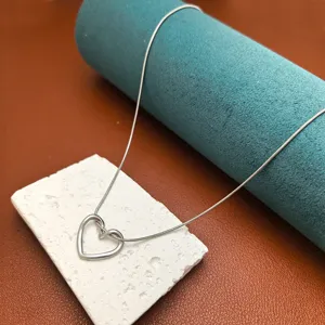 Close-up detail of silver open heart pendant necklace, trendy minimalist clavicle chain jewelry.