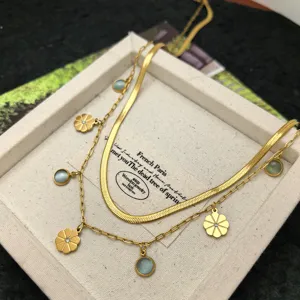 Detailed shot of double layer stainless steel necklace with floral and stone charms.