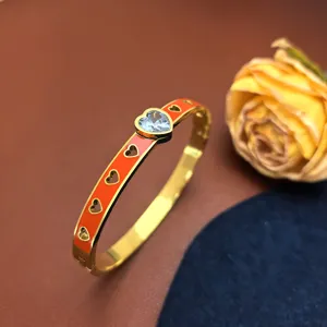 Gold titanium steel bangle bracelet with orange enamel, hollow hearts and blue crystal heart.