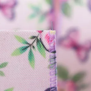 Primer plano detallado del borde de cinta floral rosa con costura overlock morada.