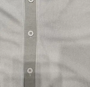 Close-up detail van heren wafelbreisel shirt sluiting en knopen textuur weergave.