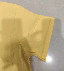Close up of yellow linen short sleeve shirt sleeve and pocket, casual summer menswear detail.