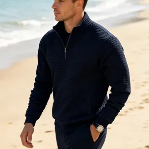 Close-up detail of a men's navy blue quarter-zip waffle knit sweatshirt on beach scene.