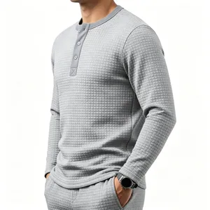 Detailed view of men's gray waffle knit long sleeve henley shirt with textured fabric.