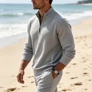 Detailed shot of men's casual light grey waffle knit quarter zip pullover on beach scene.
