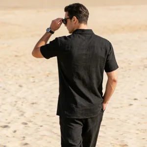 Detail shot of men's black linen short sleeve shirt, casual beach wear showing fine fabric texture.